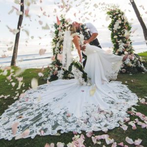 Blog - Man Holding and Kissing a Woman At Their Wedding with Petals Falling From the Sky